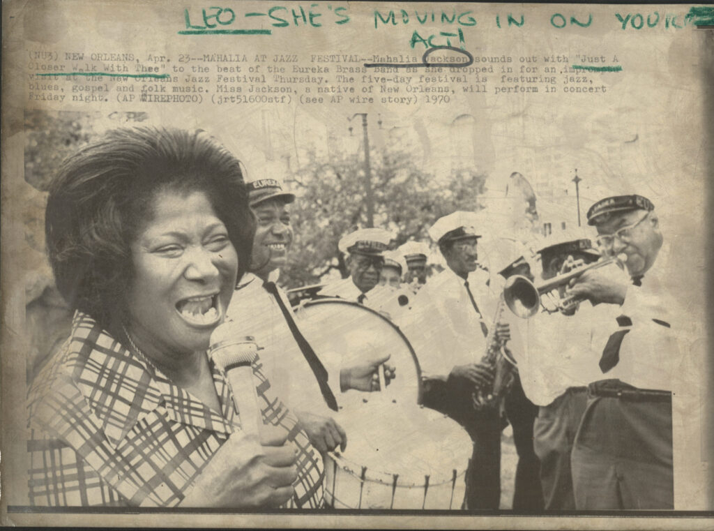 Mahalia Jackson and the Eureka Brass Band share a moment off stage and in Beauregard Square at the inaugural Jazz Fest, April 23, 1970, photographer unidentified, Laurraine Goreau collection HJA-059, LGPH0215, Tulane University Special Collections.