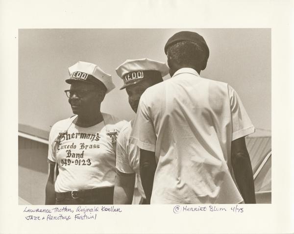 Lawrence Trotter, snare drummer, and Reginald Koeller, trumpeter, both with Sherman’s Tuxedo Brass Band; and an unidentified man stand at Jazz Fest, 1975, photographer: Harriet Blum, Hogan Archive Photography Collection, PH003950, Tulane University Special Collections.