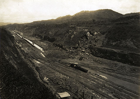 A flattened area with train tracks cut through a mountain range.