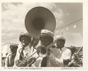 Doc Paulin’s Band performs at Jazz Fest, l. to r.: unidentified tenor saxophonist; Dwayne Paulin, sousaphone; Darryl Walker, trombone; Doc Paulin, trumpet; Michael White, clarinet; and Ricky Paulin, snare drum; 1977, photographer: Harriet Blum, Hogan Archive Photography Collection, PH003243, Tulane University Special Collections.