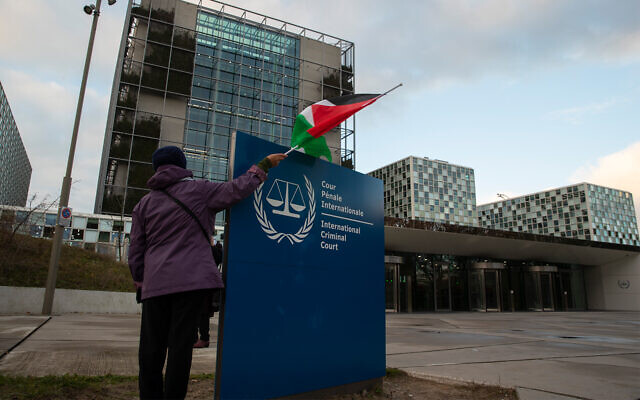 A demonstrators poses with a Palestinian flag outside the International Criminal Court (ICC) during a rally urging the court to prosecute Israel for alleged war crimes, in The Hague, Netherlands
